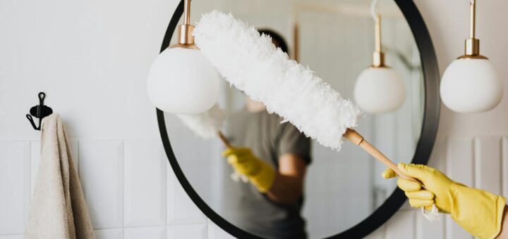 Crop woman dusting lamp during housework