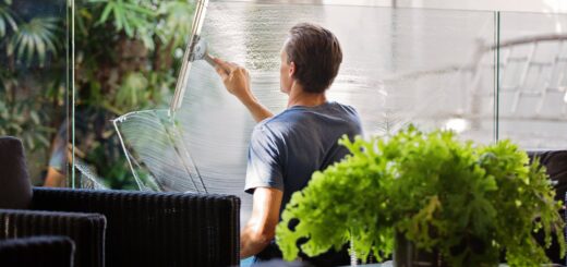 Man in Gray Shirt Cleaning Clear Glass Wall Near Sofa